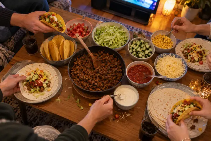 Familjen bygger egna tacos vid ett bord fullt av tillbehör